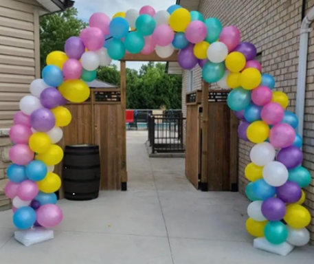 Bunte Ballonbogen in Pastellfarben, der einen Eingang schmückt.