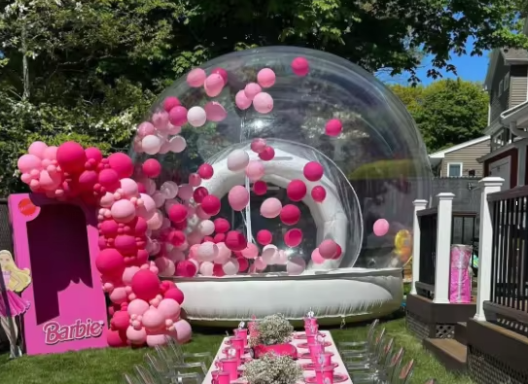 Ein transparentes Zelt mit pinken Ballons und einer festlichen Dekoration.